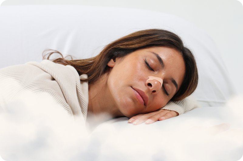 Woman sleeping peacefully on a white pillow with a neutral using nasal strips.