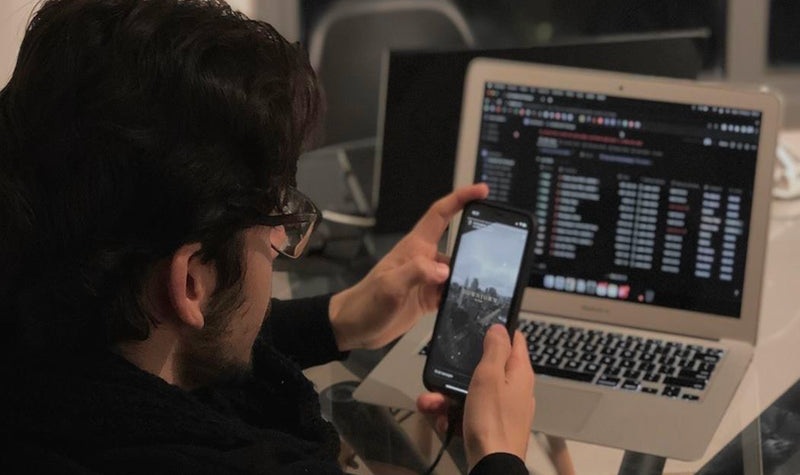 Person using a laptop and smartphone in a dimly lit room