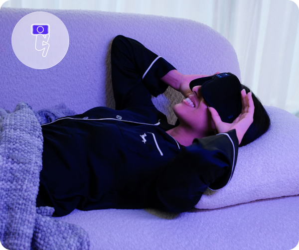 Person lying on a purple couch using Dream Bluetooth Sleep Mask by Sleep EZ
